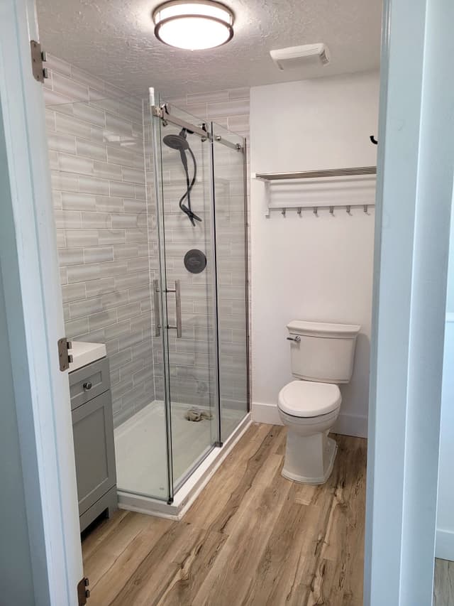 A photo of a bathroom that is almost finished. The bathroom features a glass shower, modern fixtures, and a clean design.