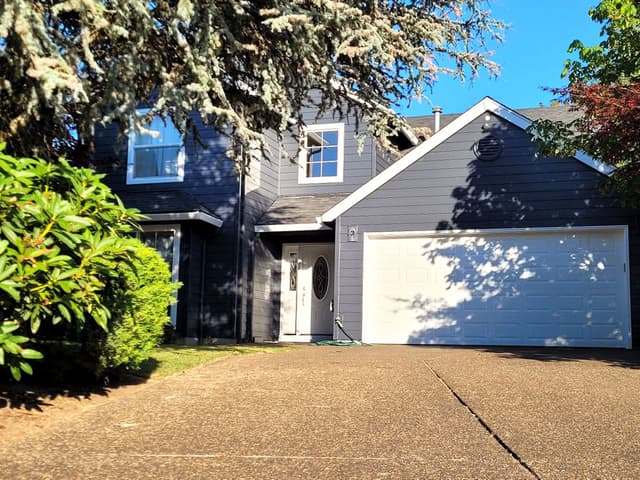 A photo of a house with a freshly painted exterior. The house is painted in a dark color with white trim.