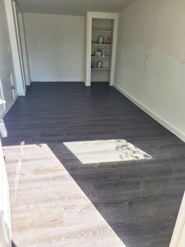 An in-progress photo of a room with new vinyl floors. The photo shows a bright, clean space with newly installed vinyl flooring and built-in shelves.