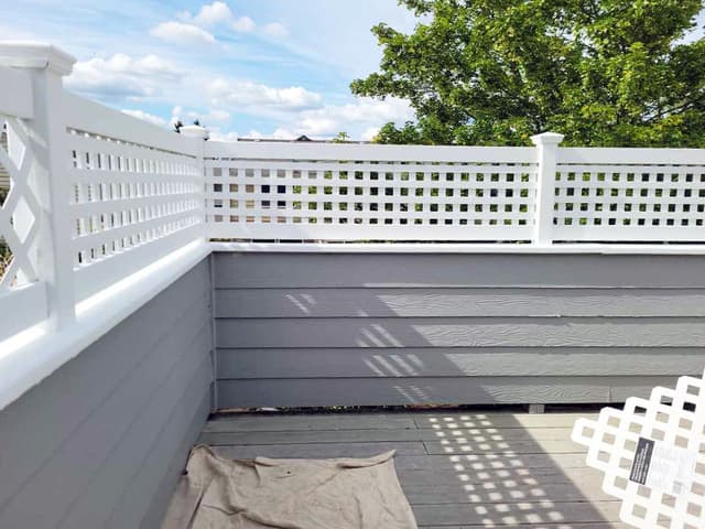 A photo of a new deck railing being installed. The railing has a white lattice design.