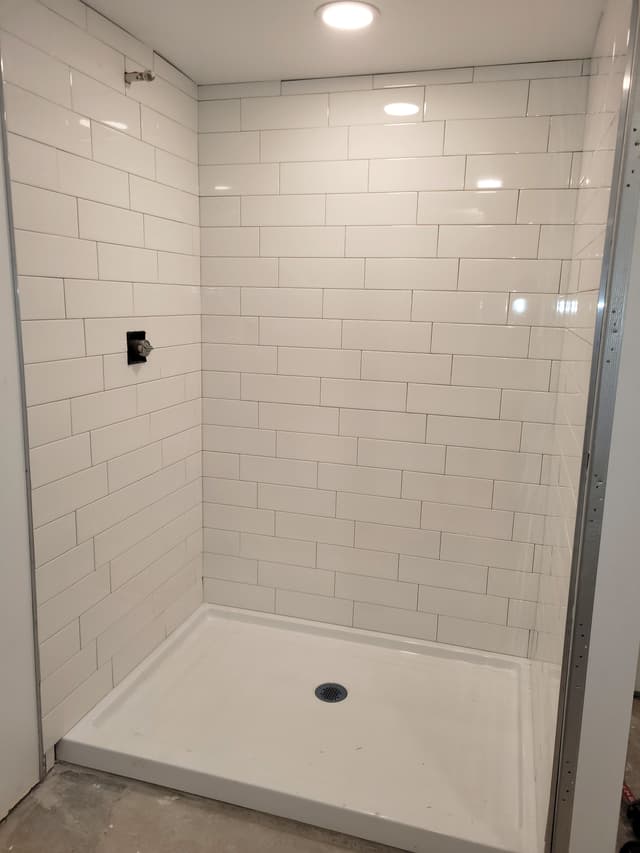 A photo of a shower area with new subway tiles being installed.