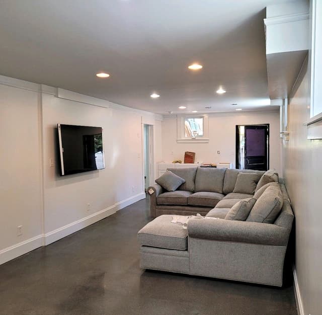 A basement family room with a polished concrete floor and a sectional sofa.