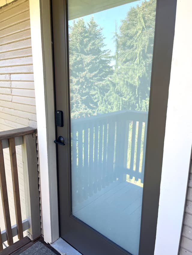 An exterior door with a fogged-glass window and a dark colored frame.